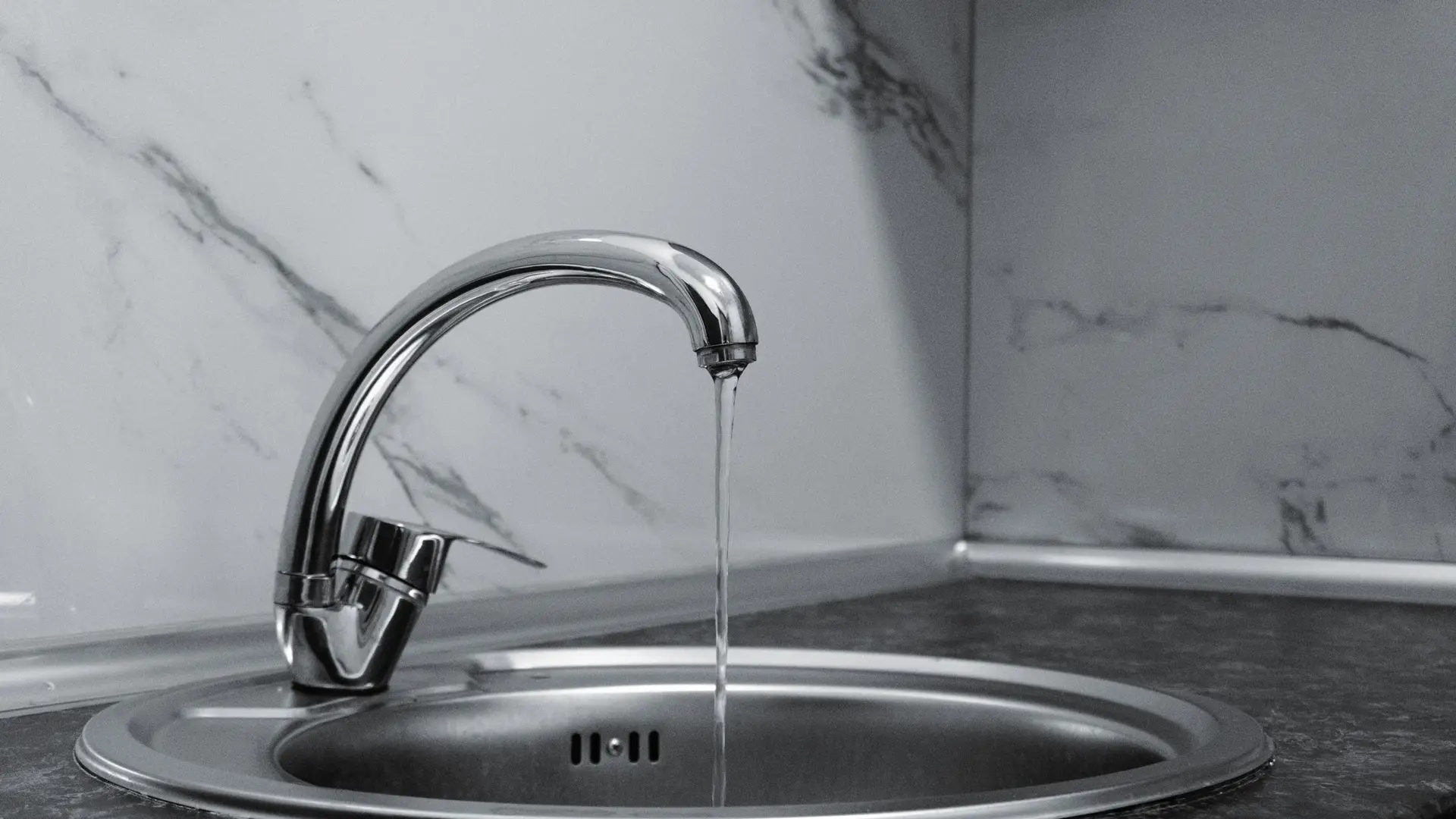 Chrome kitchen tap over a round steel sink
