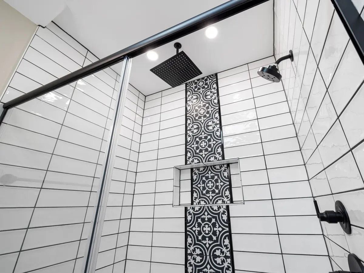 A finished tiled shower with a black-framed screen